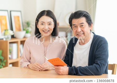 A middle-aged couple looking at their pension book at home A middle-aged couple looking at their pension book at home 136008678