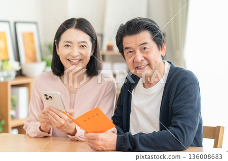 A middle-aged couple looking at their pension book at home A middle-aged couple looking at their pension book at home 136008683
