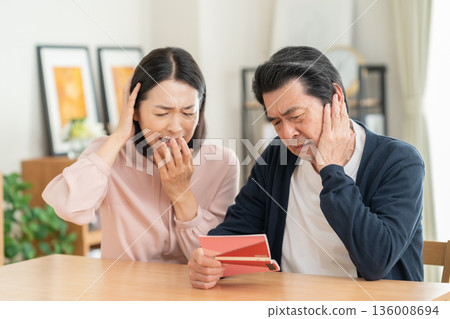 A middle-aged couple looking at their savings passbook in the living room 136008694