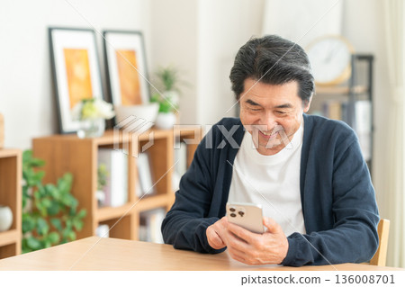 Middle man looking at a smartphone in the living room 136008701