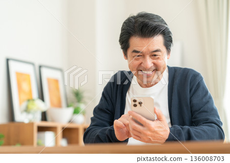 Middle man looking at a smartphone in the living room 136008703