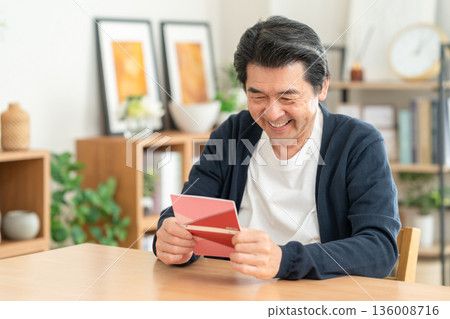 A middle-aged man looking at his savings passbook in the living room 136008716