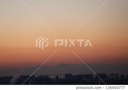 黎明前,天空色彩斑斕,城市輪廓隱約可見,一架飛機燈火通明地飛過。 黎明前,天空色彩斑斕,城市輪廓隱約可見,一架飛機燈火通明地飛過。 136008777