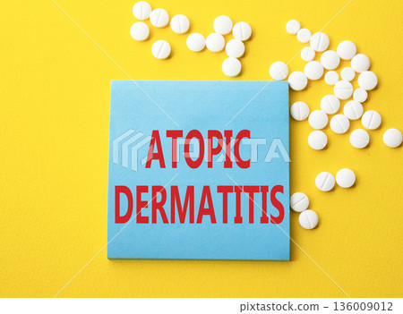 Atopic Dermatitis symbol. Concept word Atopic Dermatitis on blue note. Beautiful yellow background with pills. Medicine and Atopic Dermatitis concept. Copy space 136009012