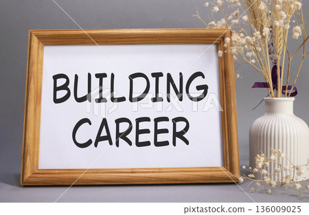 Building Career symbol. Concept words Building Career on beautiful wooden picture frame. Beautiful grey background with flower vase. Business and Building Career concept. Copy space. Building Career symbol. Concept words Building Career on beautiful wooden picture frame. Beautiful grey background with flower vase. Business and Building Career concept. Copy space. 136009025