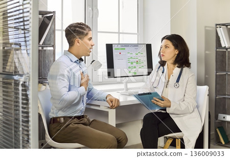Female doctor consulting male patient in modern clinic office, healthcare visit Female doctor consulting male patient in modern clinic office, healthcare visit 136009033