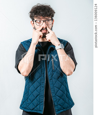 Young man with face of unpleasant odors, covering nose. Person covering nose because bad smells. Bad smells, Concept 136009124