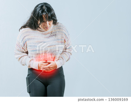 Female person holding stomach with digestive problems isolated. Sore Asian woman with digestive problems 136009169