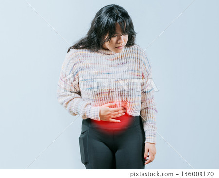 Sore Asian woman with digestive problems. Female person holding stomach with digestive problems isolated Sore Asian woman with digestive problems. Female person holding stomach with digestive problems isolated 136009170
