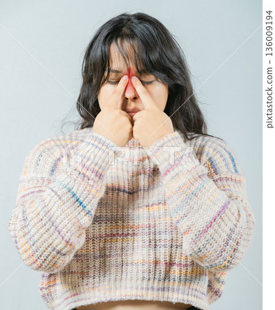 Close up of young woman with sinus pain touching nose isolated. Asian woman with rhinitis touching nose 136009194