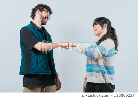 Smiling couple bumping fists, isolated. Attractive couple smiling and bumping fists 136009227