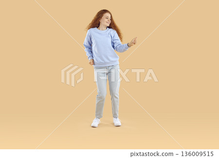 Cheerful teenage girl in good mood having fun and dancing with inspired face expression. Cheerful teenage girl in good mood having fun and dancing with inspired face expression. 136009515