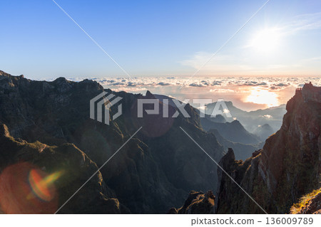 Famous viewpoint at Pico do Arieiro sunrise with bright sun above cloud sea and Atlantic horizon Famous viewpoint at Pico do Arieiro sunrise with bright sun above cloud sea and Atlantic horizon 136009789