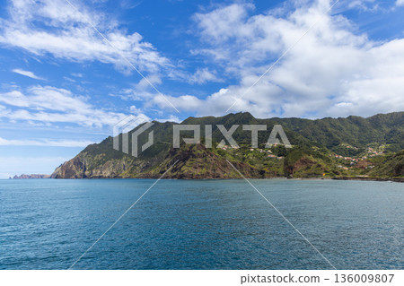 Madeira coastline near Porto da Cruz with steep mountains above Atlantic bay and village houses Madeira coastline near Porto da Cruz with steep mountains above Atlantic bay and village houses 136009807