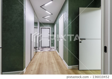 Modern apartment hallway with green textured walls and zigzag ceiling light 136010452