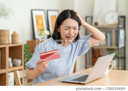A middle-aged woman looking at her savings passbook in the living room A middle-aged woman looking at her savings passbook in the living room 136010484