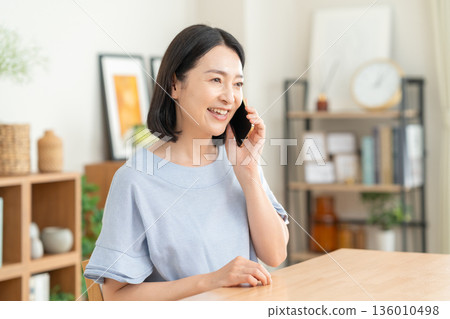 一名中年婦女在客廳裡看著智能手機 136010498