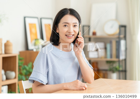 一名中年婦女在客廳裡看著智能手機 136010499