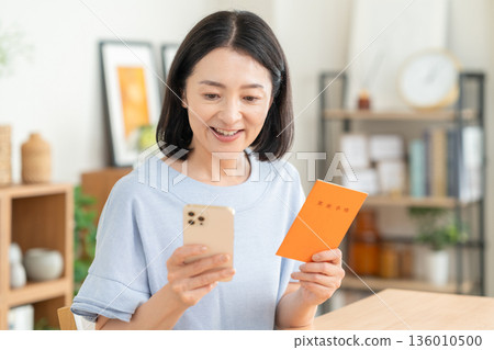 一位中年婦女在客廳看著她的退休金簿。 136010500