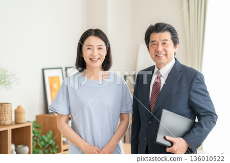 A businessman discussing business with a woman in the living room A businessman discussing business with a woman in the living room 136010522