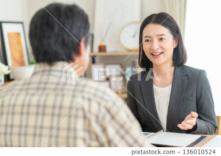 A businesswoman negotiating with a man in the living room A businesswoman negotiating with a man in the living room 136010524