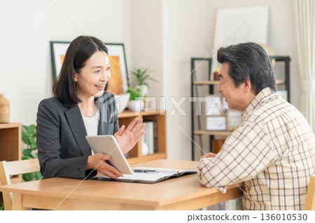 A businesswoman negotiating with a man in the living room A businesswoman negotiating with a man in the living room 136010530