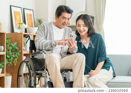 A wife caring for her middle-aged husband in the living room A wife caring for her middle-aged husband in the living room 136010568