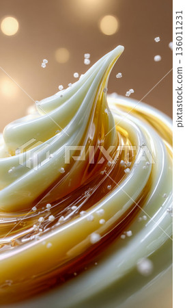 Glossy skincare cream swirl with golden honey tones and water splash droplets, clean macro texture background 136011231
