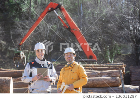 Several people working in primary industries such as forestry, measuring logs with calipers, image of building materials for real estate, smiling as they look at the camera Several people working in primary industries such as forestry, measuring logs with calipers, image of building materials for real estate, smiling as they look at the camera 136011287