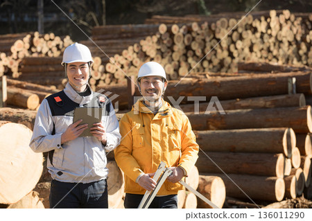 幾位從事林業等初級產業的工人正在用遊標卡尺測量原木，畫面是用於房地產的建築材料，他們看著鏡頭微笑。 136011290