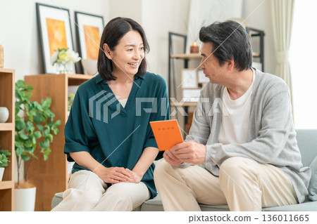 A middle-aged couple looking at their pension book at home A middle-aged couple looking at their pension book at home 136011665