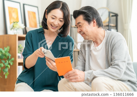 A middle-aged couple looking at their pension book at home 136011666