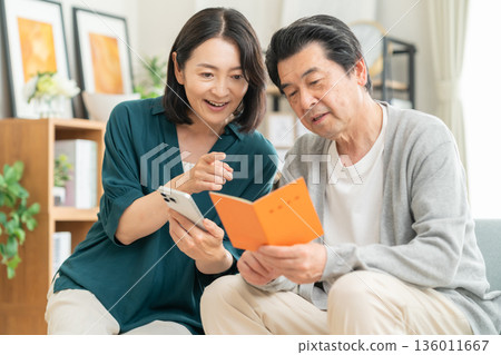 A middle-aged couple looking at their pension book at home 136011667