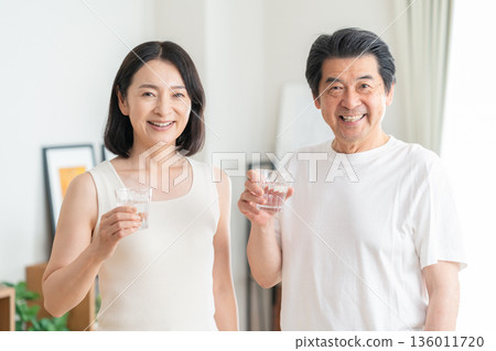 Middle-aged couple drinking water at home Middle-aged couple drinking water at home 136011720