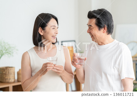 Middle-aged couple drinking water at home Middle-aged couple drinking water at home 136011721