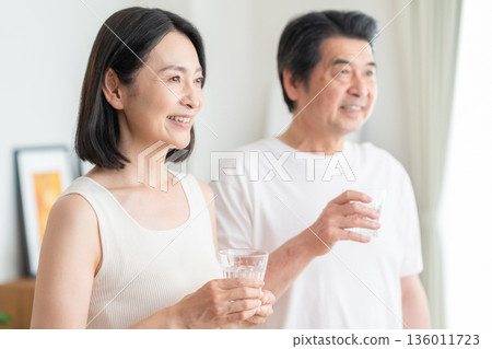 Middle-aged couple drinking water at home Middle-aged couple drinking water at home 136011723
