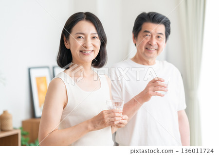 Middle-aged couple drinking water at home 136011724