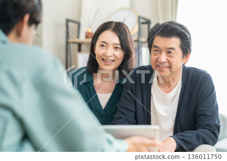 An architect negotiating with a middle-aged couple in the living room 136011750