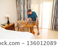 Man Rearranging Furniture in His Apartment, Embracing a Fresh Living Space and Enhancing Comfort While Infusing New Life into His Home Decor 136012089