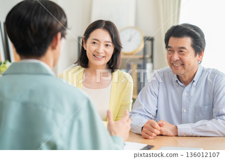 An architect negotiating with a middle-aged couple in the living room 136012107
