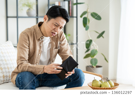 Middle-aged man holding a wallet in the living room 136012297