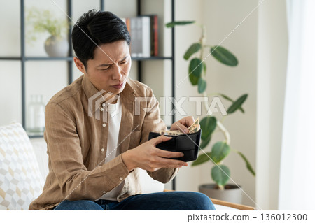 一位中年男子在客廳拿著錢包 一位中年男子在客廳拿著錢包 136012300