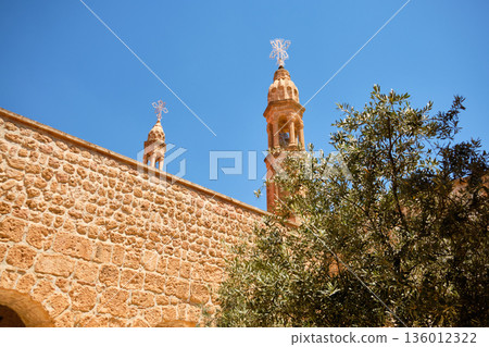 Stone church towers with crosses behind historic wall 136012322