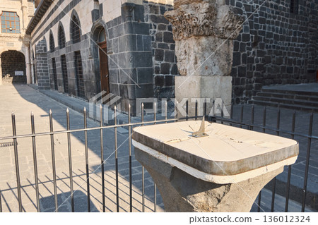 Sundial on pedestal near historic building 136012324