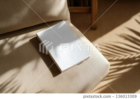 book cover mockup design. blank book template on soft beige armchair in living room or hotel room, shadow overlay book cover mockup design. blank book template on soft beige armchair in living room or hotel room, shadow overlay 136013309