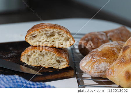 Freshly Baked Homemade Ciabatta Bread Cooling on a Rack and Cut Open on a Board Freshly Baked Homemade Ciabatta Bread Cooling on a Rack and Cut Open on a Board 136013602