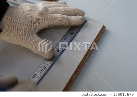 戴著工作手套的手用尺測量木板，DIY 和精確測量 136013676