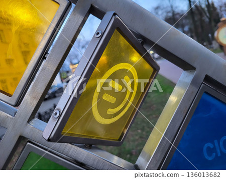 A rotating yellow square with a funny face on a stained-glass window in the street 136013682