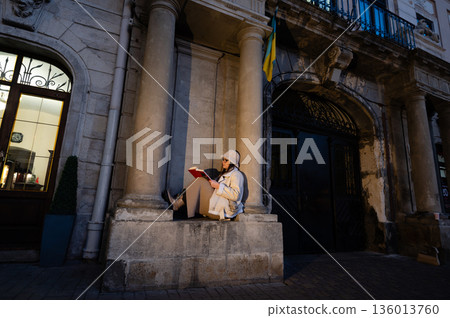 Quiet reading moment at night in front of a historic building with tall columns and a flag waving gently in the wind 136013760