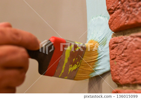 Outdoor wall painting by color brush. Handyman painting concrete block wall. Outdoor wall painting by color brush. Handyman painting concrete block wall. 136015099